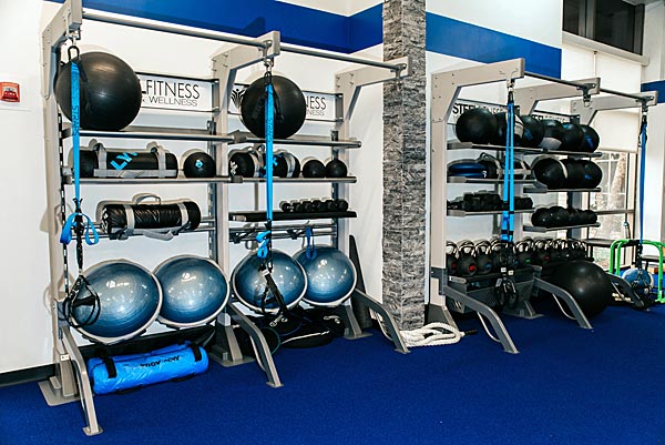 Rack with kettlebells, bosu balls, and yoga balls at fitness floor of Steel Fitness Premier.