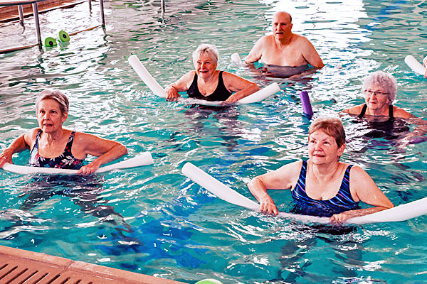 Men and women taking an aquatics exercise class for seniors in an indoor pool.