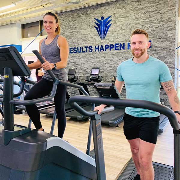 Man and woman using cardio equipment in the gym at Steel Fitness Premier.